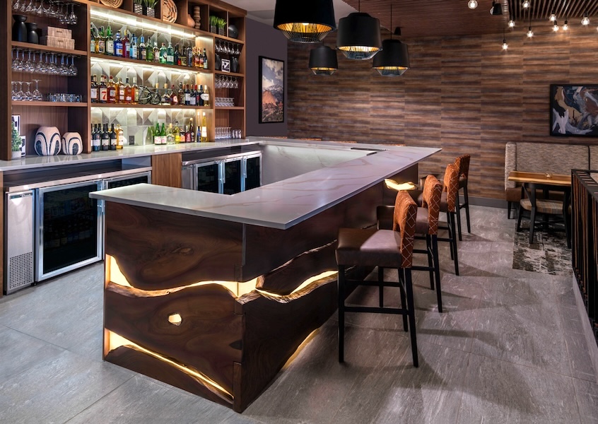 Sculpted live-edge bar with illuminated front and quartz countertop at Ryze Skyline Lounge