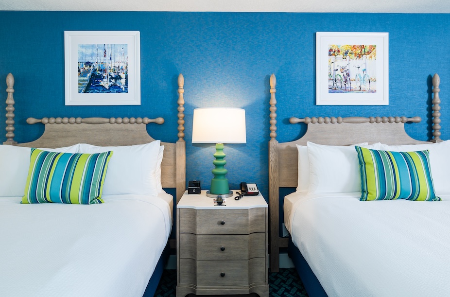 Guest room with two beds, blue accent wall, and striped pillows at Lake View Hotel.